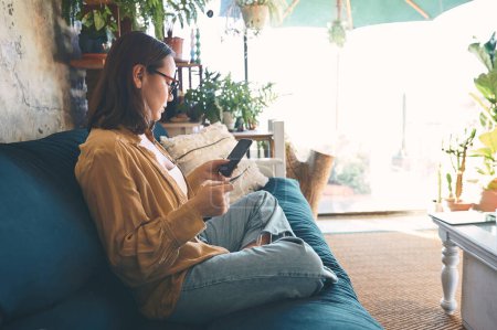Photo for What would lockdown be without online shopping. a young woman using a smartphone and credit card on the sofa at home - Royalty Free Image