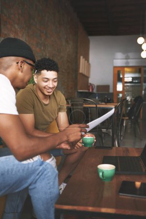Foto de Hazme saber lo que piensas de mis ideas. dos jóvenes discutiendo negocios mientras están sentados juntos en una cafetería - Imagen libre de derechos
