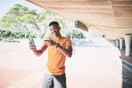 Foto de Sígueme para tu dosis diaria de fitness inspo. un joven usando un teléfono inteligente y auriculares durante un entrenamiento sobre un fondo urbano - Imagen libre de derechos