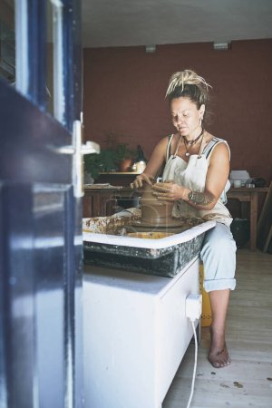 Téléchargez les photos : Le chemin de l'accomplissement se trouve à la roue de la poterie. une jeune femme travaillant avec de l'argile dans un atelier de poterie - en image libre de droit