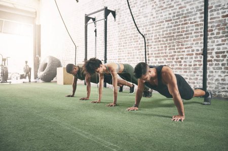 Photo for When youre part of a fitness group, youre motivated for longer. a fitness group doing push-ups at the gym - Royalty Free Image
