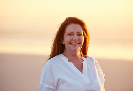 Photo for You cant beat that vacation feeling. mature woman standing on the beach at sunset - Royalty Free Image