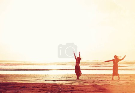 Téléchargez les photos : Si tu veux être libre, sois libre. deux jeunes femmes passent la journée à la plage au coucher du soleil - en image libre de droit