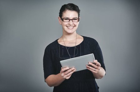 Foto de Personalmente, es la mejor tableta para mí. Retrato de estudio de una joven empresaria usando una tableta digital sobre un fondo gris - Imagen libre de derechos