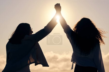 Photo for Back silhouette, sunshine and women holding hands for support, success and love in nature. Happy, dark and friends with solidarity, trust and unity on a holiday for friendship or bonding together. - Royalty Free Image