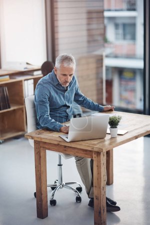 Foto de Entrando en acción con sus ideas innovadoras. un hombre de negocios maduro que trabaja en un ordenador portátil en una oficina - Imagen libre de derechos