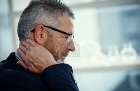 Foto de Su cuello está mostrando la peor parte de los asuntos estresantes. un hombre de negocios maduro que experimenta dolor de cuello en el trabajo en una oficina moderna - Imagen libre de derechos
