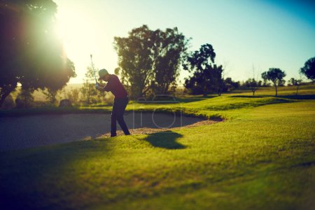 Photo for One swing to get it to the green. a young man hitting the ball out of the bunker during a round of golf - Royalty Free Image