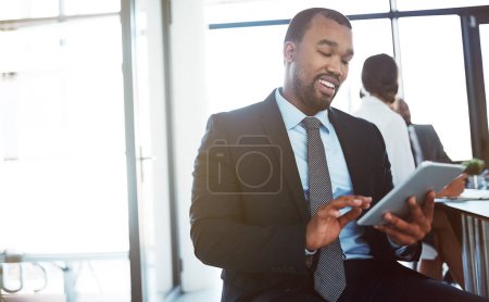 Téléchargez les photos : L'exec connecté est un exec courant. un jeune homme d'affaires utilisant une tablette numérique lors d'une réunion au travail - en image libre de droit
