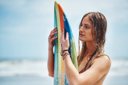 Téléchargez les photos : Il est temps d'attraper quelques vagues. une jolie jeune femme debout sur une plage avec une planche de surf - en image libre de droit