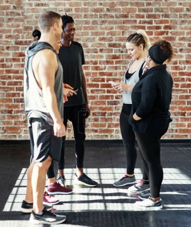 Photo for Take two. a cheerful young group of people standing in a circle and having a conversation before a workout in a gym - Royalty Free Image