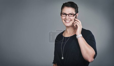 Téléchargez les photos : Succès sur appel. Plan studio d'une jeune femme d'affaires utilisant un téléphone portable sur fond gris - en image libre de droit