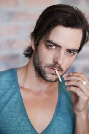 Téléchargez les photos : Il a beaucoup d'attitude. Portrait d'un bel homme fumant sa cigarette - en image libre de droit