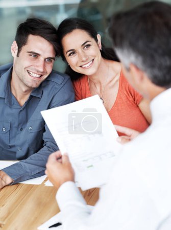 Photo for Your bond application has been approved. Happy young couple in a meeting with a financial consultant - Royalty Free Image