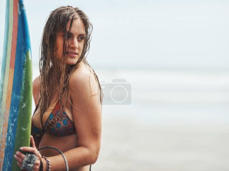 Téléchargez les photos : Il est temps d'attraper quelques vagues. une jolie jeune femme debout sur une plage avec une planche de surf - en image libre de droit
