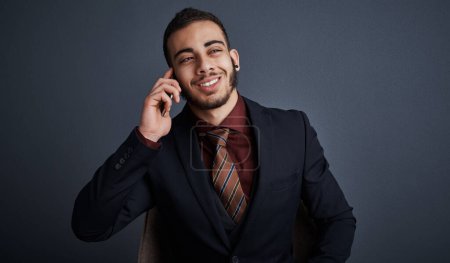 Photo for Give me the good news. Studio shot of a stylish young businessman looking thoughtful while making a phonecall against a gray background - Royalty Free Image