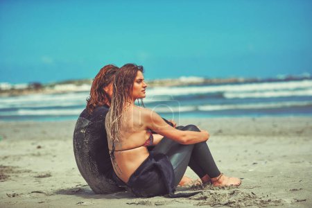 Téléchargez les photos : Ce ne serait pas un surf sans un copain de surf. un jeune couple surfant sur la plage - en image libre de droit