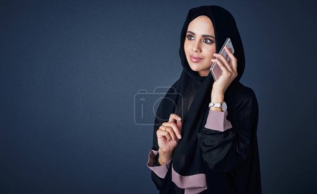 Téléchargez les photos : Se connecter avec des gens qui comptent. Plan studio d'une jeune femme portant une burqa et utilisant un téléphone portable sur fond gris - en image libre de droit