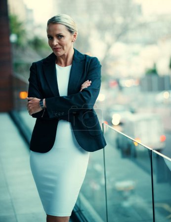 Foto de La confianza me llevó lejos en mi carrera. Retrato de una mujer de negocios madura parada afuera en el balcón de su oficina corporativa - Imagen libre de derechos