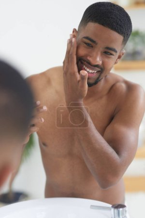 Photo for Happy man, face and beauty with mirror and skincare, hygiene and grooming during morning routine at home. Black male person smile in bathroom, fresh and clean facial with wellness and moisturizing. - Royalty Free Image