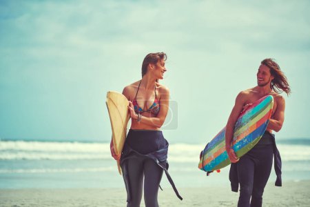 Foto de Eran almas gemelas. una joven pareja caminando por la playa con sus tablas de surf - Imagen libre de derechos