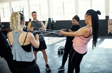 Photo for You can achieve so much more together. a fitness group working out with resistance bands in their session at the gym - Royalty Free Image