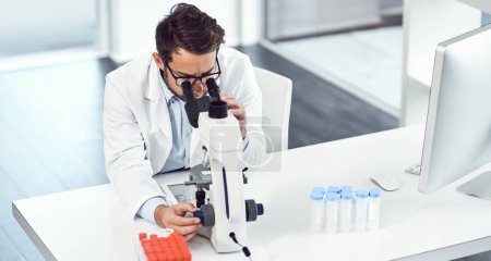 Photo for Looking straight into another world. a focused young male scientist looking through a microscope inside of a laboratory - Royalty Free Image