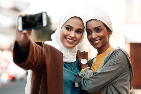 Photo for Muslim woman, selfie and social media in city together with happiness, outdoor or urban adventure. Islamic women, profile picture and photography for travel blog, app and friends on road in metro cbd. - Royalty Free Image