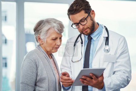 Photo for I need you to stay aware of these symptoms. a doctor discussing something on a digital tablet with a senior patient in a clinic - Royalty Free Image
