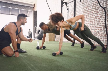 Photo for It takes dedication and a good instructor to reach your goals. two people working out with a fitness instructor at the gym - Royalty Free Image