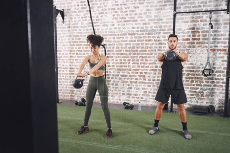 Photo for The more time you spend at the gym, the more time you gain. two sporty young people using kettlebells while working out at the gym - Royalty Free Image