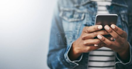 Photo for Hands, cellphone and woman with texting by wall background with typing, mockup space or email on web. Student girl, smartphone and chat for blog, post or video on social network app for communication. - Royalty Free Image