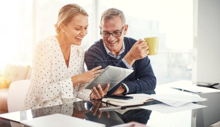 Photo for Home admin just got smarter. a mature couple using a digital tablet while going through paperwork at home - Royalty Free Image