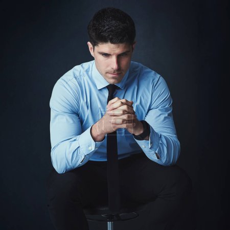 Photo for Some decisions require deep thought. Studio shot of a young businessman looking thoughtful against a dark background - Royalty Free Image