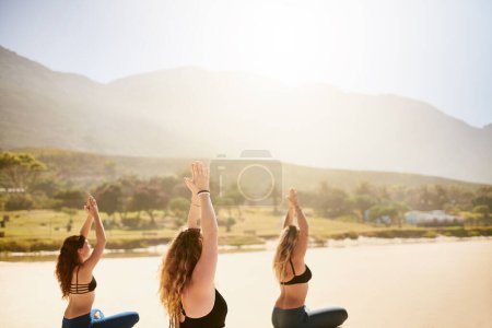 Photo for Yoga gives you the means to develop patience. three young women practising yoga on the beach - Royalty Free Image