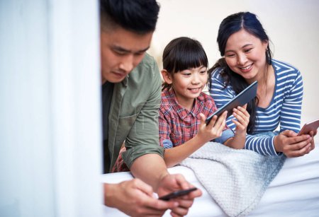 Téléchargez les photos : C'est une famille qui aime les merveilles de la technologie. une famille utilisant des appareils numériques à la maison - en image libre de droit