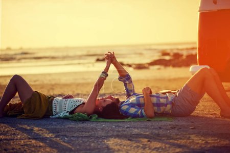Photo for Lets never part. an affectionate young couple holding hands while lying on the beach - Royalty Free Image