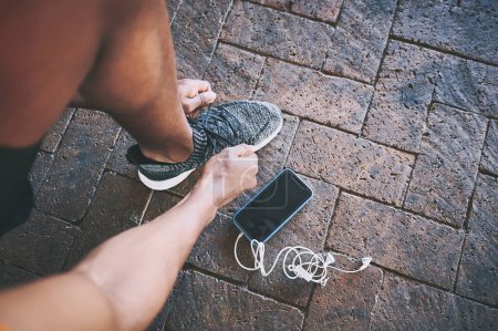 Téléchargez les photos : Mets tes chaussures de course et bouge. un homme attachant ses lacets lors d'une séance d'entraînement sur fond urbain - en image libre de droit