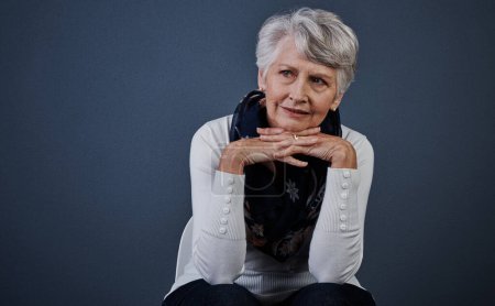 Photo for Take me back to the good old days. Studio shot of cheerful elderly woman sitting with her hands under her chin while looking into the distance - Royalty Free Image