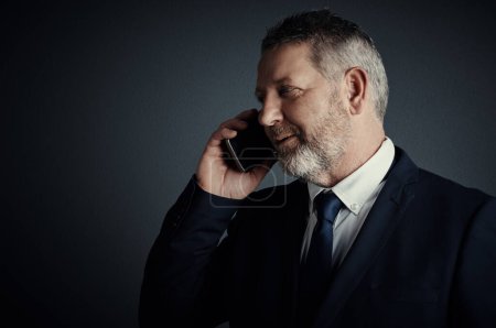 Photo for You have news for me. Studio shot of a handsome mature businessman looking thoughtful while making a call against a dark background - Royalty Free Image