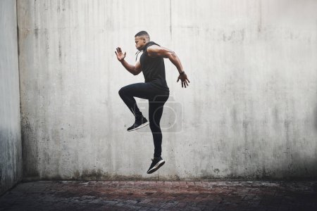 Photo for Jump, training and black man running, speed and energy for cardio fitness, workout and sports wellness or body health. Athlete, runner or person exercise on concrete wall, action run or moving in air. - Royalty Free Image