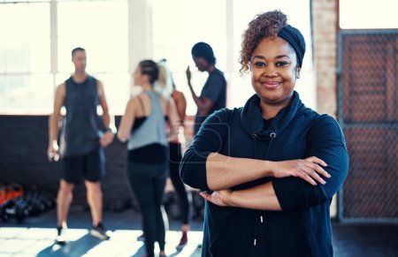 Photo for Looking professional. Portrait of a cheerful young woman standing with her arms folded while looking into the camera before a workout in a gym - Royalty Free Image