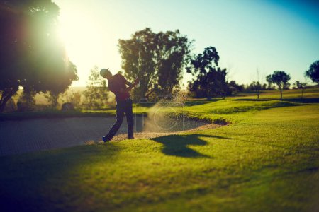 Photo for Out of the sand trap and onto the greens. a young man hitting the ball out of the bunker during a round of golf - Royalty Free Image
