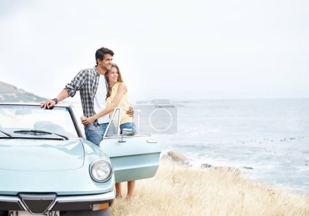 Téléchargez les photos : Bénéficiant d'une belle vue. Un jeune couple romantique debout à côté de leur décapotable lors d'un voyage en voiture - en image libre de droit