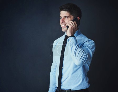 Photo for He can close any deal with just one call. Studio shot of a young businessman talking on a cellphone against a dark background - Royalty Free Image