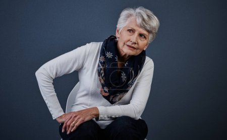 Photo for Age may change but class stays the same. Studio shot of a elderly woman sitting down with her one hand on her hip while looking onto the distance - Royalty Free Image