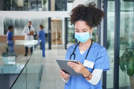 Photo for Technology limits chaos in the clinic. an attractive young nurse standing and wearing a face mask while using a digital tablet - Royalty Free Image