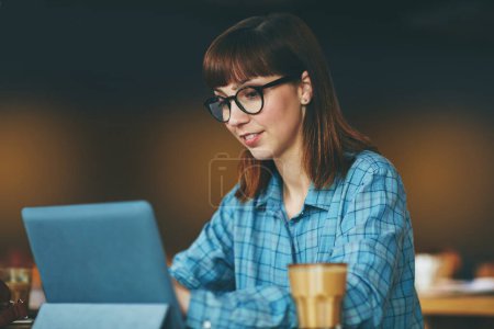 Photo for Her blog is creating quite some hype online. an attractive young woman using a digital tablet in a cafe - Royalty Free Image