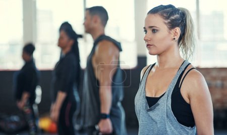 Photo for Keep calm and collective. a focused group of young people standing in a row and training with weights in a gym - Royalty Free Image