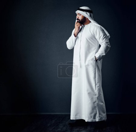 Foto de Nunca dejes de pensar en cómo mejorar. Estudio de un joven vestido con ropa tradicional islámica posando sobre un fondo oscuro - Imagen libre de derechos